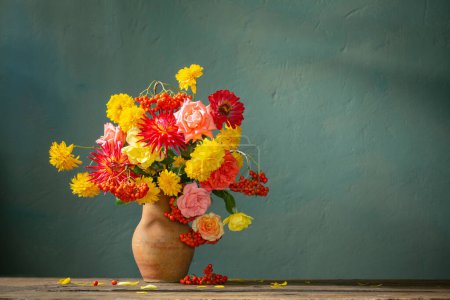 Photo for Red and yellow flowers on jug in sunlight on background dark wall - Royalty Free Image