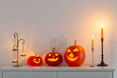 Foto de Calabazas de halloween con velas encendidas en el interior blanco - Imagen libre de derechos