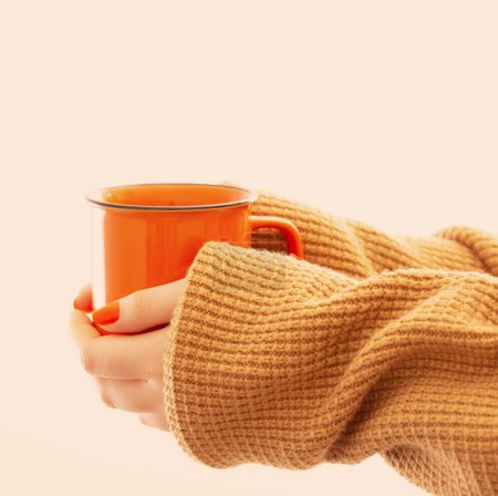 Téléchargez les photos : Mains féminines avec une tasse de café orange sur fond blanc - en image libre de droit