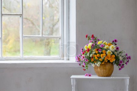 Foto de Ramo de crisantemos de colores en jarrón en el interior blanco viejo - Imagen libre de derechos