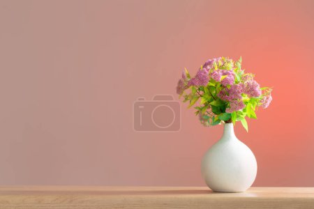 Foto de Spirea rosa en jarrón blanco en estante de madera - Imagen libre de derechos