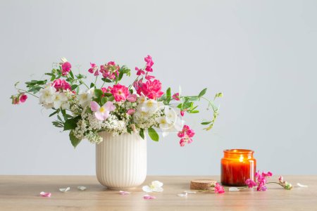 Foto de Flores de verano y velas encendidas sobre fondo claro - Imagen libre de derechos