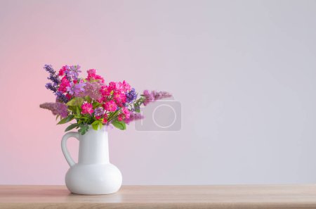 Foto de Hermosas flores en jarra blanca en estante de madera - Imagen libre de derechos