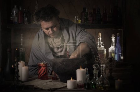 Téléchargez les photos : Homme alchimiste faire potion dans chambre noire - en image libre de droit
