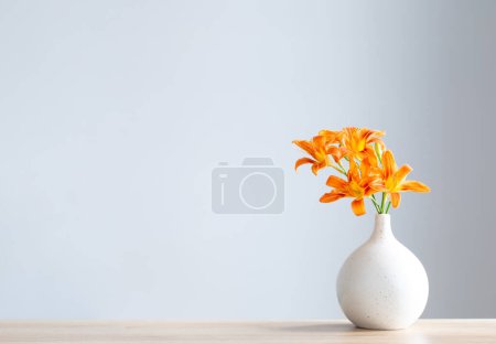 Foto de Flores de verano en jarrón moderno blanco en estante de madera - Imagen libre de derechos