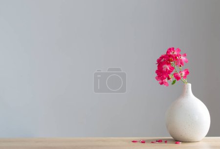 Photo for Pink roses in ceramic vase on wooden table - Royalty Free Image