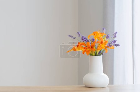 Summer flowers in white jug on wooden shelf