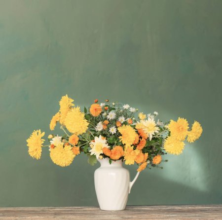 Foto de Crisantemo amarillo y blanco en jarra blanca sobre mesa de madera - Imagen libre de derechos