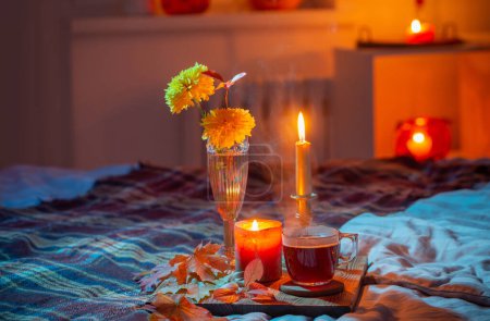Foto de Taza de té y crisantemo en jarrón con velas encendidas en el dormitorio - Imagen libre de derechos