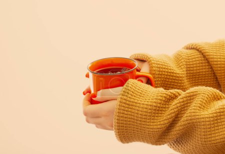 Foto de Manos femeninas con taza de café naranja sobre fondo amarillo - Imagen libre de derechos