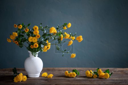 Photo for Yellow chrysanthemums in white vase on background dark wall - Royalty Free Image