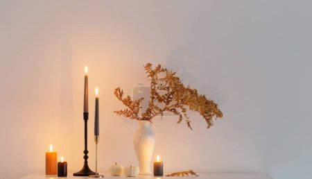 Foto de Hermosa decoración casera de otoño con velas encendidas en el interior blanco - Imagen libre de derechos