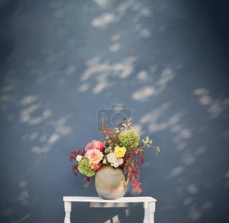 Photo for Autumn flowers and berries  in rustic ceramic jug on background blue wall - Royalty Free Image