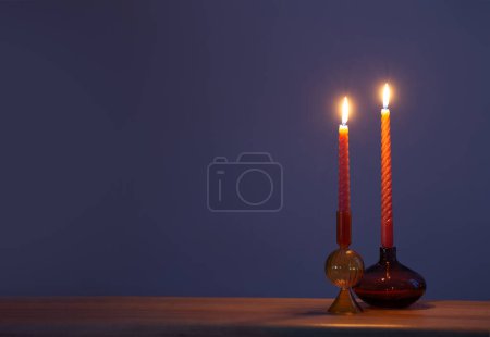 Téléchargez les photos : Bougies allumées dans des chandeliers en verre sur fond bleu foncé - en image libre de droit