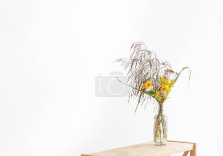 Téléchargez les photos : Bouquet de roseaux et fleurs automnales jaunes en bouteille sur fond blanc - en image libre de droit