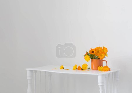 Foto de Ramo con caléndulas de color naranja en taza sobre fondo blanco - Imagen libre de derechos
