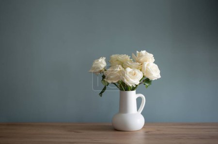 Téléchargez les photos : Bouquet de roses blanches en cruche en fond bleu mur - en image libre de droit