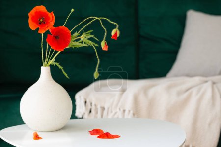 Photo for Red poppies in vase in modern cozy interior with green coach - Royalty Free Image