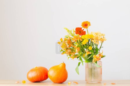 Foto de Ramo de otoño y calabazas de color naranja en el estante de madera en la pared gris de fondo - Imagen libre de derechos