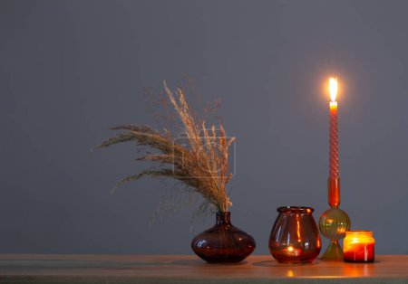 Photo for Dried flowers and burning candles on background dark wall - Royalty Free Image
