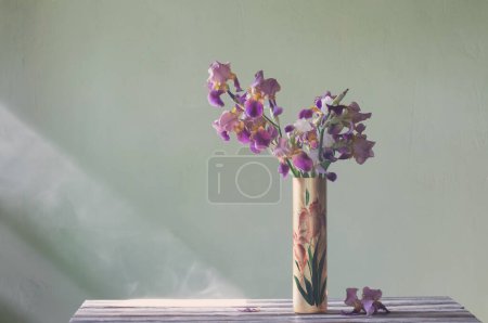Téléchargez les photos : Iris dans un beau vase en verre contre le mur vert - en image libre de droit