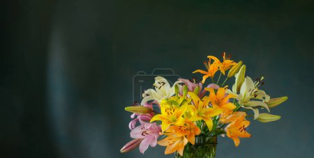 Photo for Beautiful  lilies in glass green vase on dark background - Royalty Free Image