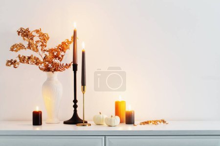 Photo for Beautiful autumn home decor with burning candles in white interior - Royalty Free Image