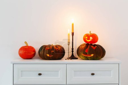 Photo for Halloween pumpkins with burning candles in white interior - Royalty Free Image