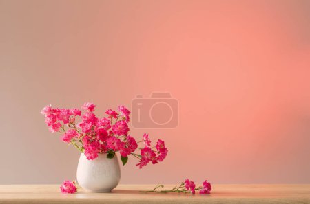 Photo for Pink roses in ceramic vase on light red background - Royalty Free Image