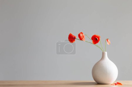 Téléchargez les photos : Coquelicots rouges dans un vase sur fond gris - en image libre de droit