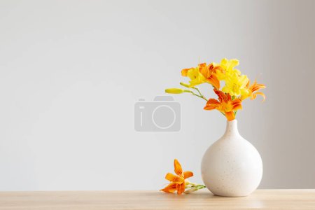 Photo for Summer flowers in white modern vase on wooden shelf - Royalty Free Image