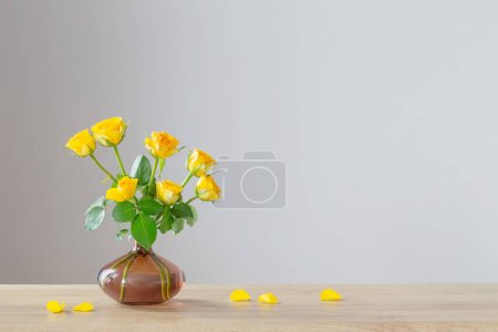 Téléchargez les photos : Roses jaunes en cruche blanche sur étagère en bois - en image libre de droit