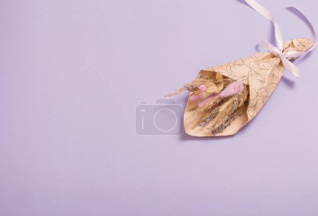 Foto de Ramo de flores secas en papel artesanal sobre fondo lila - Imagen libre de derechos