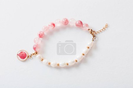 pink and white bracelet made of natural stones on white background