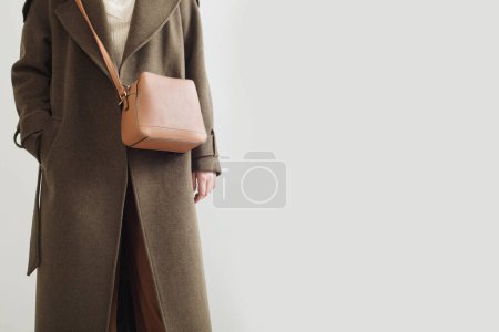Téléchargez les photos : Jeune femme en manteau d'automne avec sac à main sur fond blanc - en image libre de droit