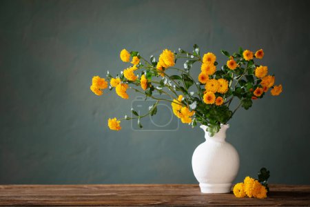 Téléchargez les photos : Chrysanthèmes jaunes dans un vase blanc sur fond sombre mur - en image libre de droit