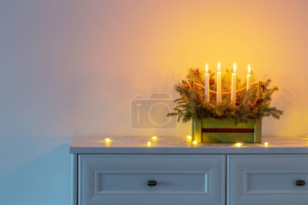 Foto de Adviento decoración con ramas de abeto y cuatro velas encendidas en canasta de madera sobre fondo blanco - Imagen libre de derechos