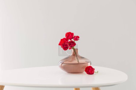 Photo for Red roses in modern glass vase in white interior - Royalty Free Image