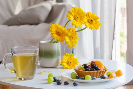 Foto de Magdalenas con frutas y té verde en la mesa blanca en casa - Imagen libre de derechos