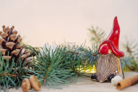 Téléchargez les photos : Gnome de céramique en chapeau rouge avec branches de Noël et décor naturel - en image libre de droit