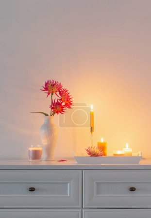 Photo for Beautiful pink dahlia in white vase and burning candles on white background - Royalty Free Image