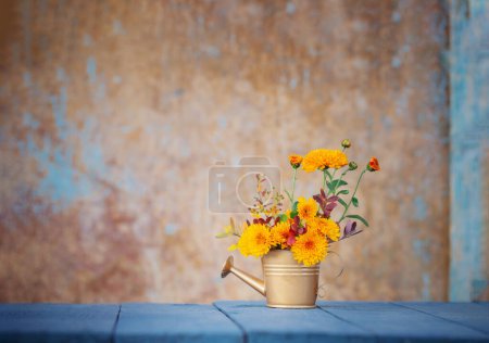 Photo for Chrysanthemum flowers in golden watering can  on background old wall in sunlight - Royalty Free Image