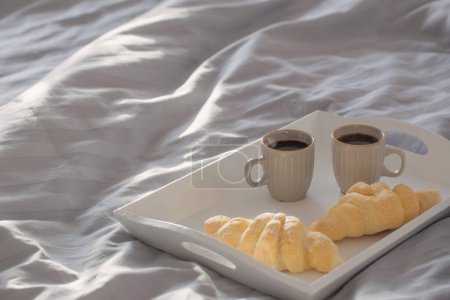 Foto de Dos croissants y dos tazas de café en la cama - Imagen libre de derechos
