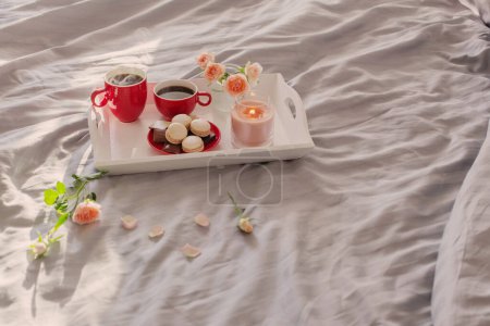 Foto de Dos tazas rojas de café y flores en la cama - Imagen libre de derechos