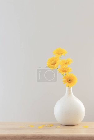 Téléchargez les photos : Gerbera jaune dans un vase moderne sur étagère en bois - en image libre de droit