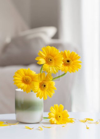 Foto de Gerberas amarillas en jarrón de cerámica en sala de estar ligera - Imagen libre de derechos