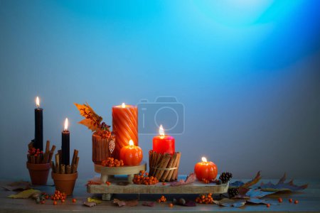 Photo for Autumn decor with burning candles on wooden shelf on blue background - Royalty Free Image