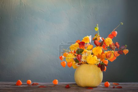 Photo for Pumpkin with autumnal bouquet on dark background - Royalty Free Image