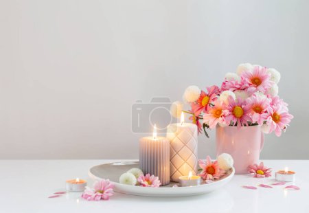 Photo for Burning candles and pink and white  chrysanthemums in white interior - Royalty Free Image