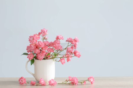 Foto de Rosas rosadas en jarrón de cerámica sobre fondo azul - Imagen libre de derechos